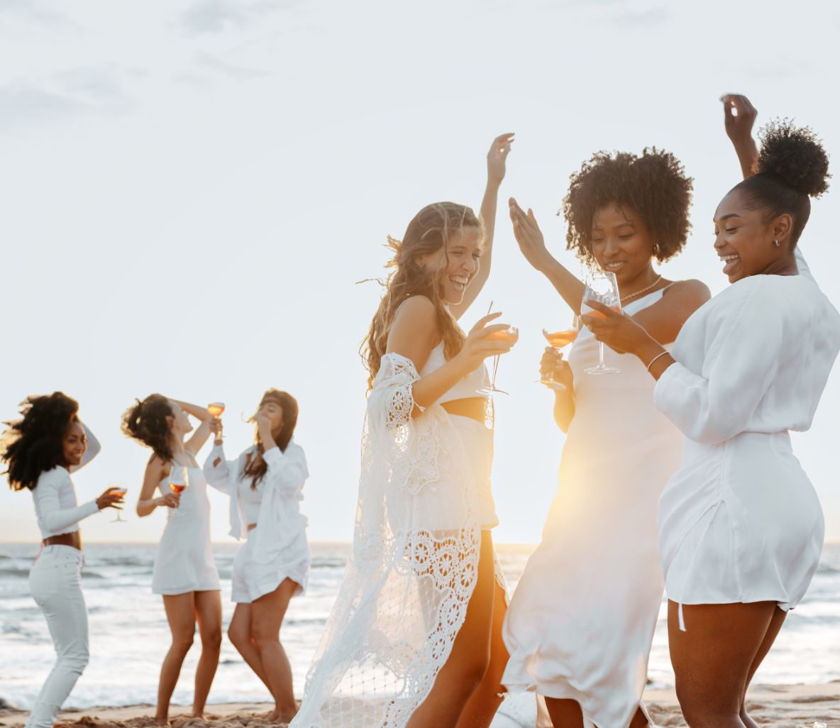 Friends dancing on the beach at sunset
