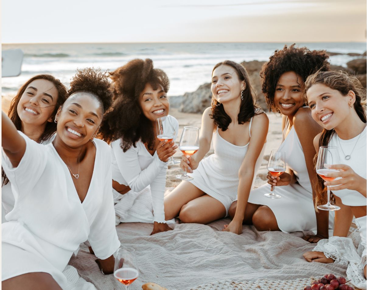 Friends toasting with rosé at a beach picnic