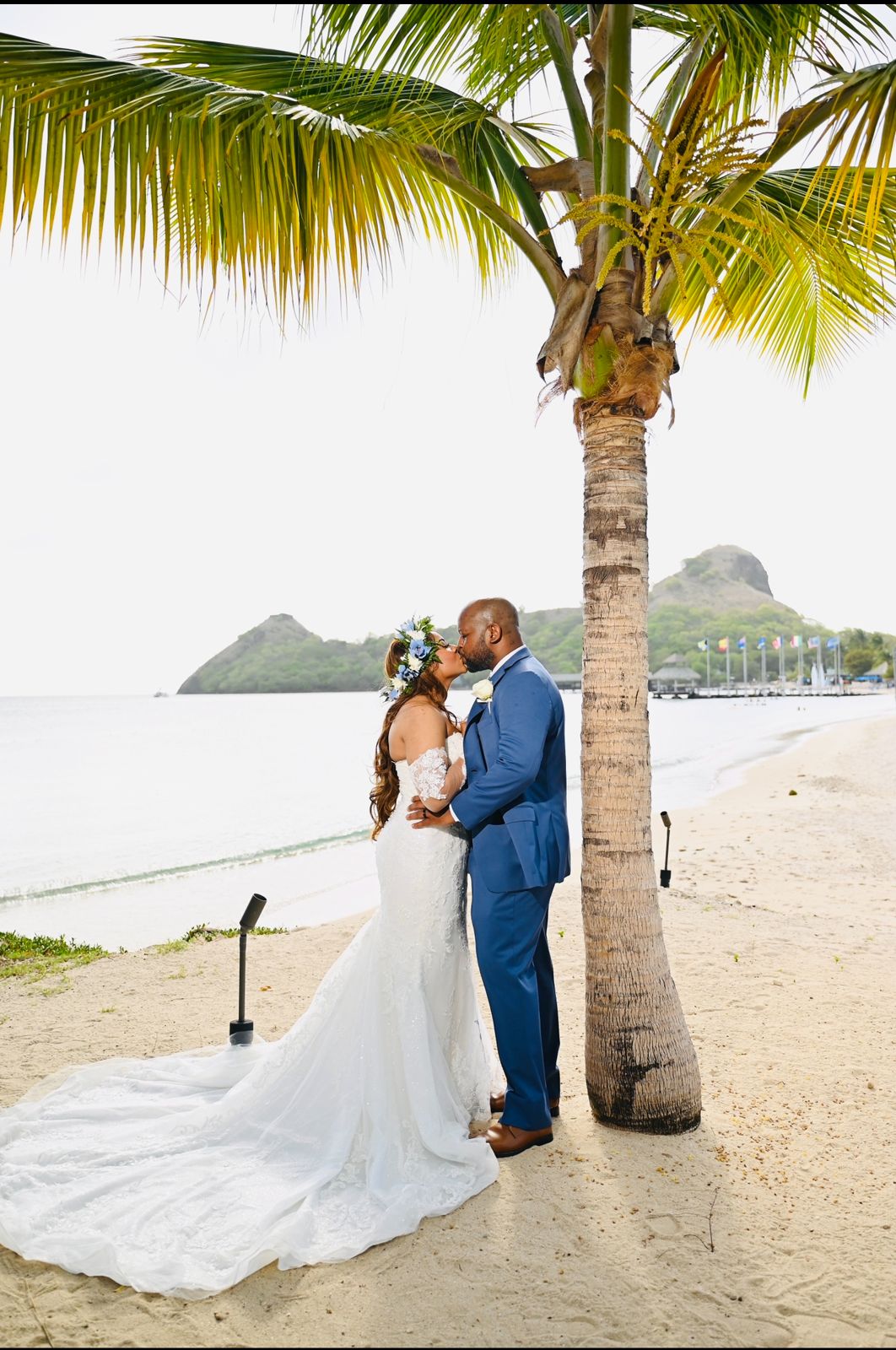 Bride and groom kissing under a palm tree on a St. Lucia beach